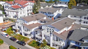 A coastal residential area with multi-story houses, some with balconies, and a view of the sea.