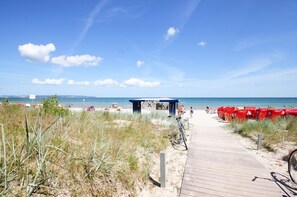 A beach with a wooden boardwalk leading to a beach bar. - Directly on the beach promenade, balcony with sea view - Aparthotel Ostsee FeWo 35 (Binz)