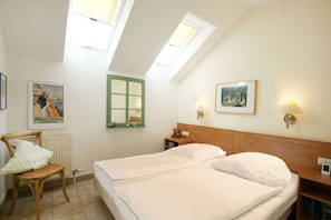 A bedroom with two beds, a wooden headboard, a nightstand, a chair, a radiator, a green-framed window, and two wall-mounted lamps. - Directly on the beach promenade, balcony with sea view - Aparthotel Ostsee FeWo 35 (Binz)
