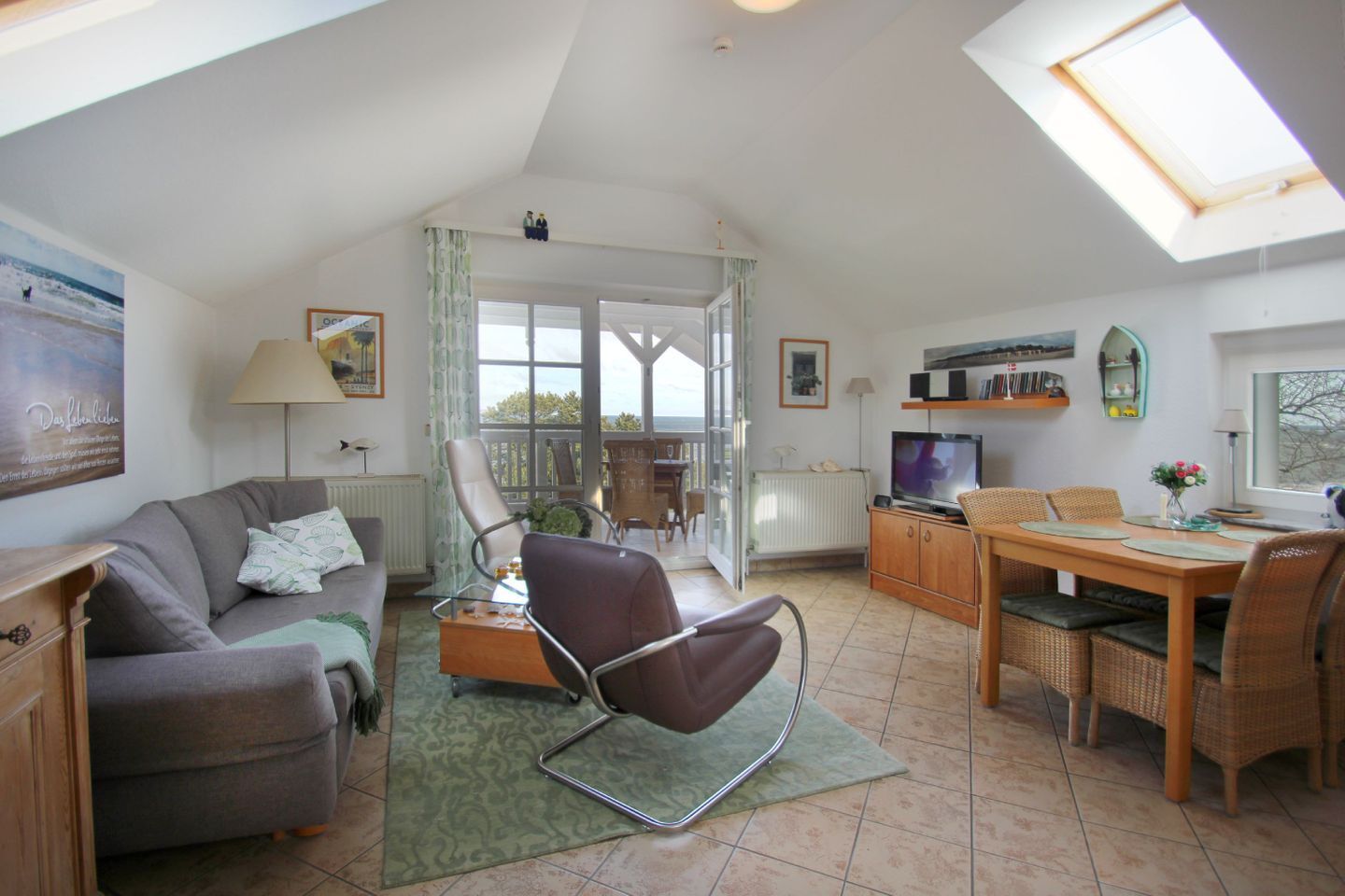 Een ruime woonkamer met een bank, fauteuil, eettafel en televisie.