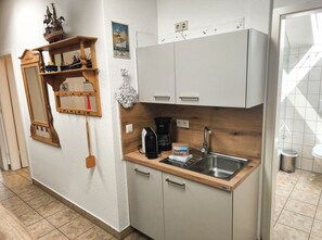 Une cuisine compacte dotée d’un plan de travail en bois, d’un évier encastré et d’une machine à café.