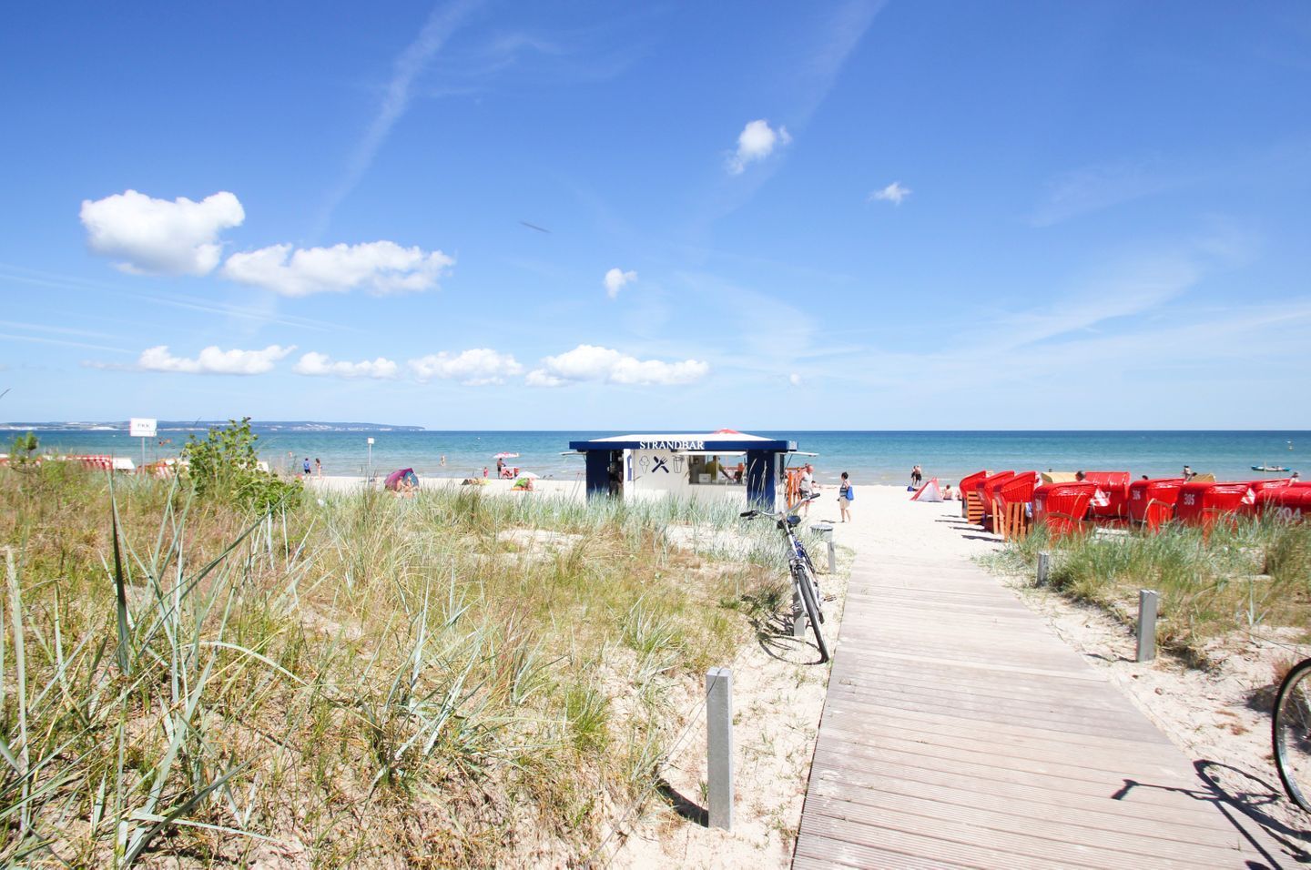 Une plage avec une promenade en bois qui mène à un bar de plage.