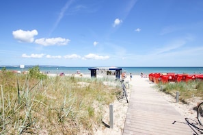 A beach with a wooden boardwalk leading to a beach bar.