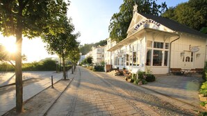 En hyggelig, hvid bygning med et skilt, der siger "Strandhalle", og et overdækket udendørs siddeområde.