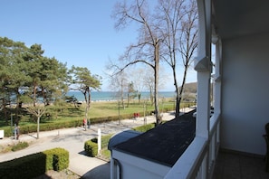 A balcony with a view of a park, a pathway, and a body of water. - Directly on the beach promenade, balcony with sea view - Aparthotel Ostsee FeWo 10 (Binz)