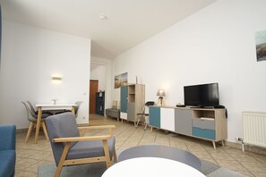 Un salon moderne comprenant un coin repas, un téléviseur et une petite table.