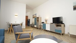 Un salon moderne comprenant un coin repas, un téléviseur et une petite table.