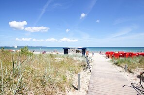 A beach with a wooden boardwalk leading to a beach bar.