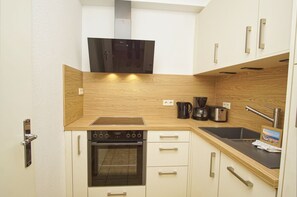 A compact kitchen with a built-in oven, a stovetop, a coffee maker, and a sink.