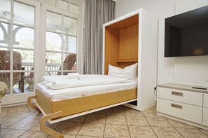Une chambre avec un lit, une télévision et une fenêtre avec des rideaux.