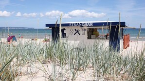 A beachside food kiosk named STRANDBAR with a clear view of the ocean and beach in the background. - Directly on the beach promenade, balcony with sea view - Aparthotel Ostsee FeWo 15 (Binz)