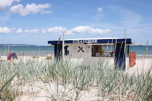 A beachside food kiosk named STRANDBAR with a clear view of the ocean and beach in the background.