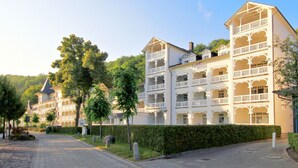Um hotel com vários andares, varandas e um caminho no jardim.