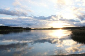 A calm lake at sunset with a clear sky and distant hills.