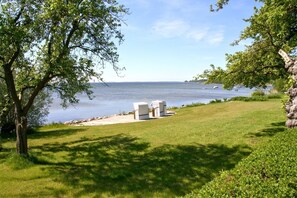 A grassy area with a white outdoor seating area and a view of a lake. - Beachfront idyll by the sea, private bathing area - Gutshof Ostseeblick FeWo 01 - (Putbus)