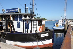 A boat docked at a pier with a sign reading "Räucherschiff BERTA". - A Seaside Getaway, Private Swimming Area - Gutshof Ostseeblick FeWo 01 - (Putbus)