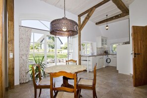 Une cuisine spacieuse avec un coin repas, de grandes fenêtres et un luminaire suspendu.