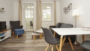 Un salon moderne comprenant un téléviseur, un canapé, une table à manger et des chaises.