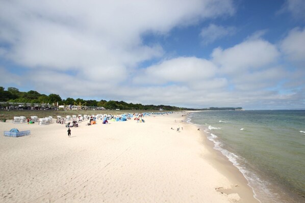 A wide sandy beach with tents and people.