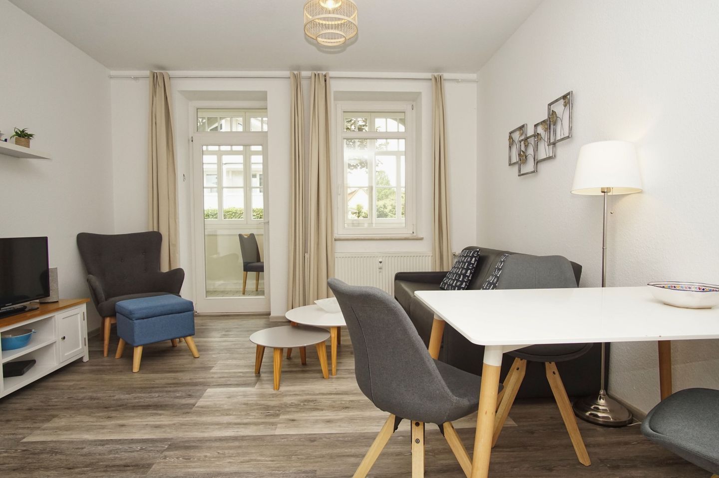 Ett modernt vardagsrum med tv, soffa, matbord och stolar.