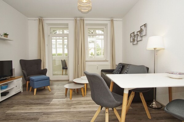 A modern living room with a TV, sofa, dining table, and chairs.