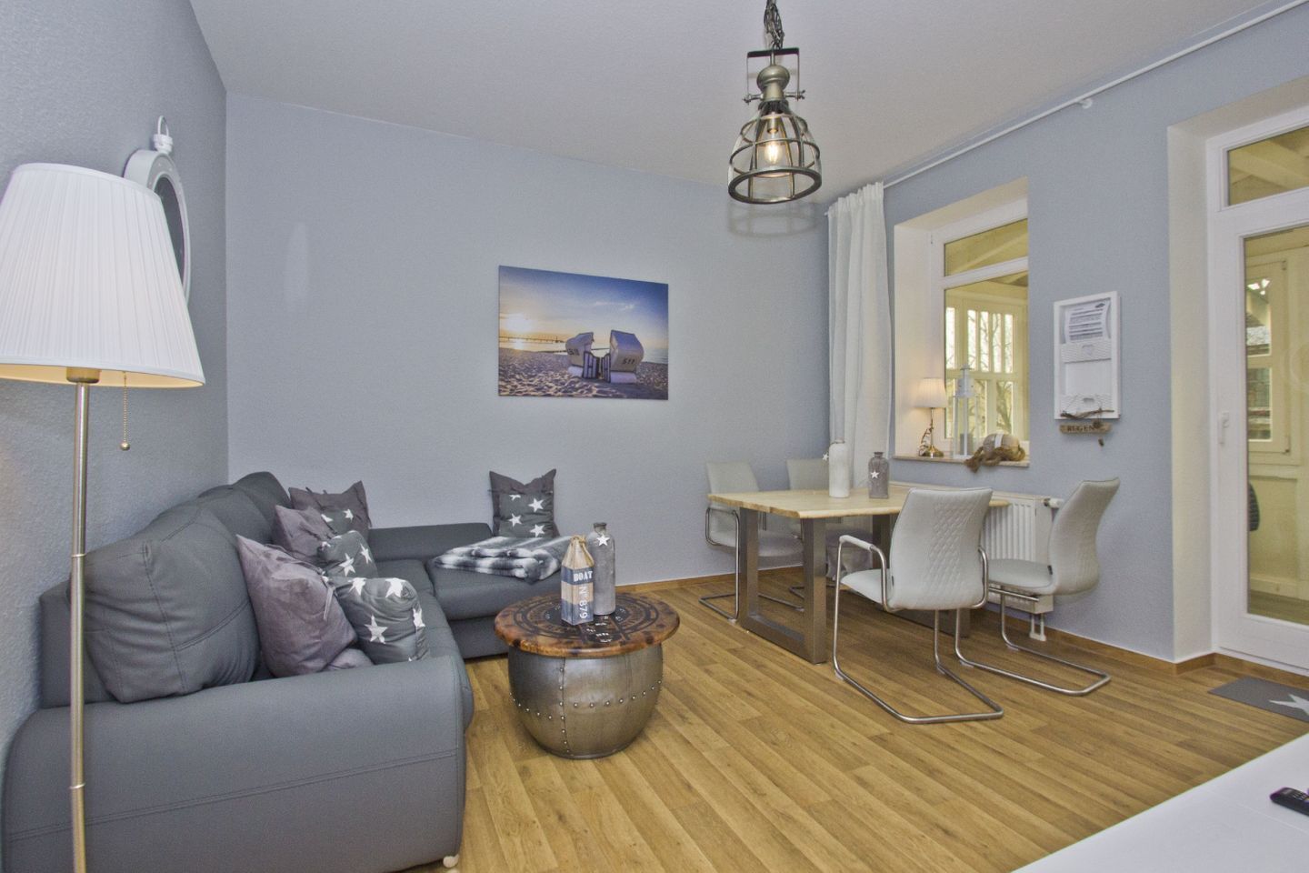 A modern living room with a grey sofa, a round coffee table, and a dining area with a table and chairs.