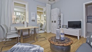 Un salon moderne avec une table à manger en bois, deux chaises, un canapé, un téléviseur et un tabouret décoratif.