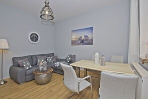 A modern living room with a grey sofa, a wooden coffee table, and a dining table with chairs. - Quiet location, beach-style vacation apartment with a veranda - Villa Möwe FeWo 04 - (Göhren)