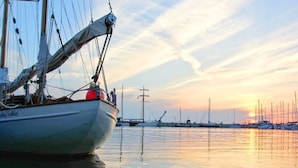Un bateau était amarré dans une marina, l’eau était calme et le soleil se couchait à l’horizon.