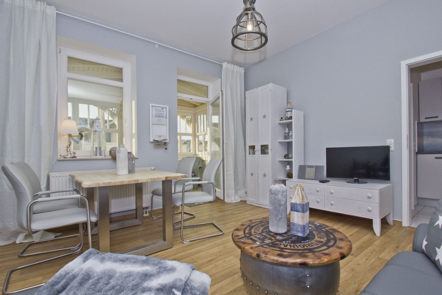 Un salon moderne avec une table à manger en bois, deux chaises, un canapé, un téléviseur et un tabouret décoratif.