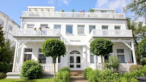 A two-story building with a white facade, a balcony with white railings, and a sign that reads "Villa Käthe". - Quiet location with terrace, use of swimming pool and sauna - Villa Käthe FeWo 04 - (Göhren)