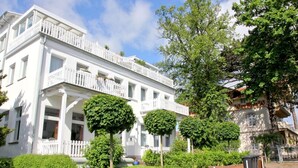 A white building with a balcony and a garden. - Quiet location with terrace, use of swimming pool and sauna - Villa Käthe FeWo 04 - (Göhren)
