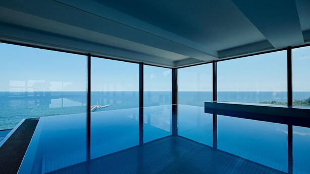 A modern infinity pool with a clear view of the ocean and a pier in the distance. - Pool and sauna with sea view, directly at the pier - FIRST Sellin FeWo 2.3 - (Sellin)