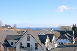 Ein Wohngebiet mit Häusern, die Schrägdächer und viele Fenster haben, mit Blick auf ein Gewässer.