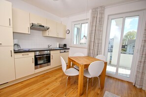 Una cucina moderna con mobili bianchi, elettrodomestici in acciaio inossidabile e un tavolo da pranzo in legno con sedie bianche.