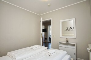 A hotel room with two beds, a mirror, and a door leading to another room. - Die Ferienwohnung Nr. 27 in der Villa Buskam - Villa Buskam (Göhren)