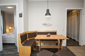A modern hotel room with a wooden bench and table, a wall-mounted light, and a sign reading "ESS Klasse". - Die Ferienwohnung Nr. 27 in der Villa Buskam - Villa Buskam (Göhren)