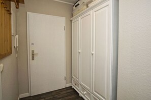 Ein Flur mit einer weißen Tür und einem großen, weißen Kleiderschrank.
