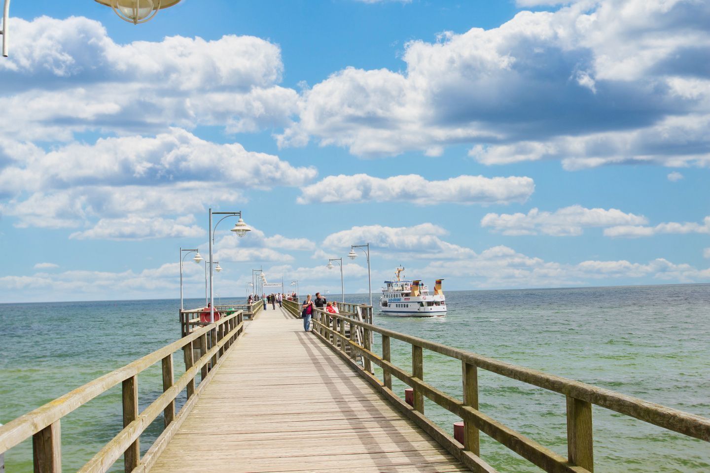 A wooden pier extending into the water with a boat in the distance.