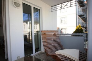 Ein Balkon mit einer Holzbank, einem weißen Handtuch und Blick auf Gebäude.