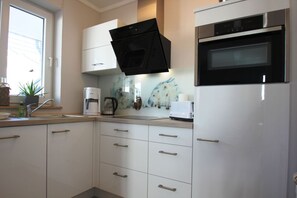 Eine moderne Küche mit weißen Schränken, einer schwarzen Mikrowelle, einer Kaffeemaschine und einem Toaster.