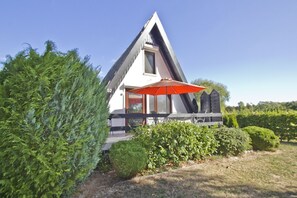 Een modern huis met een puntig dak, een groot raam en een rode paraplu.