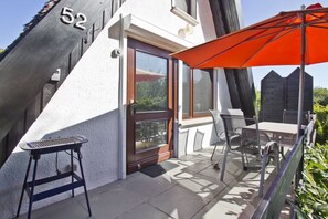 Een modern gebouw met een balkon, een deur en een bord met het nummer 52.