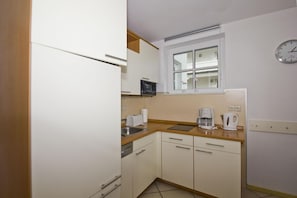 A compact kitchen with a refrigerator, a microwave, a coffee maker, and a toaster. - Apartment with a view of the sea, access to the pool and sauna - Haus Blick zur See FeWo 01 - (Göhren)