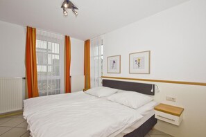 Un dormitorio con cama, mesita de noche y ventana con cortinas.