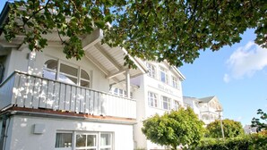 A two-story building with a balcony and large windows. - Apartment with sea view, use of swimming pool and sauna - Haus Blick zur See FeWo 01 - (Göhren)