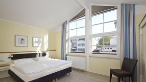Et hotelværelse med en seng, en stol, et natbord og et vindue med gardiner.