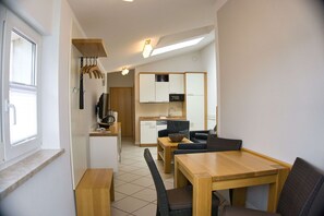 Un espacio habitable compacto con kitchenette, un área de comedor con mesa y sillas, y una pequeña zona de estar con sofá.