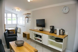 Una cocina moderna con televisor de pantalla plana, cafetera, tostadora y un reloj en la pared.