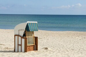 A beach chair with a striped canopy on a sandy beach. - Apartment with sea view, use of swimming pool and sauna - Haus Blick zur See FeWo 11 - (Göhren)